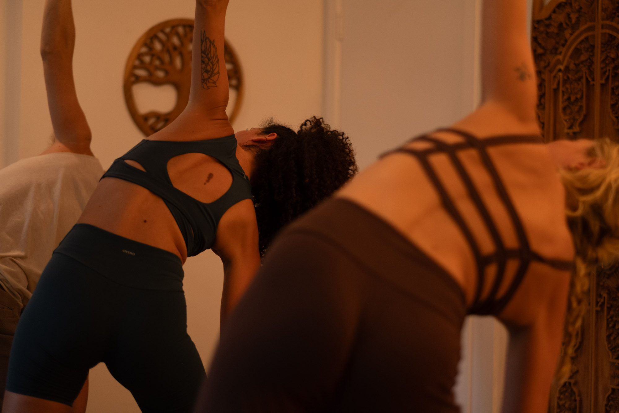 Students moving through a side bend together in the warm candlelit studio
